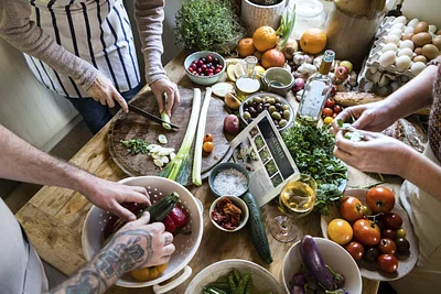 People preparing fresh vegetables for cooking around a worktable.