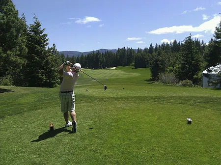 A man has just hit the golf ball, and waiting for it to land.