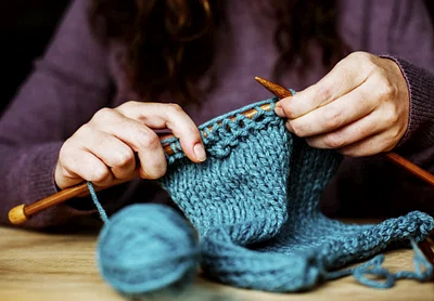 A pair of hand knitting with bright blue wool.