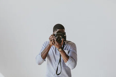 A woman holds a camera right in the foreground of the photo.
