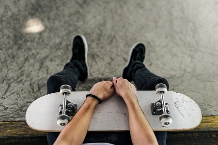 A person holds a skateboard while sitting.