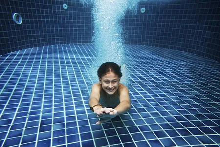 A women swims at the bottom of the pool floor.